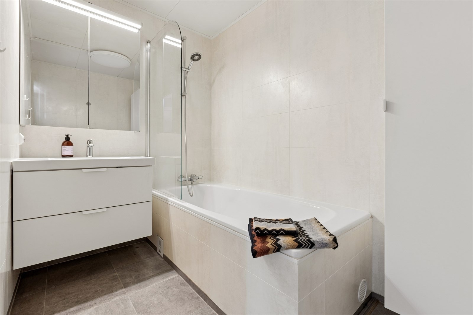Badet er utsytrt med lys innredning, badekar og speil m/led-lys. Galleribilde