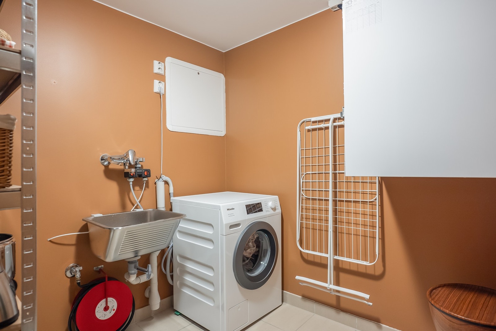 Leiligheten har også et eget vaskerom på romslige 4,5 kvm. Dette frigjør plass på badet og gjør hverdagen enklere. Det er flislagt gulv og rommet er malt i samme farge som gjestetoalett, i fargen "Natural Clay". Rommet har også utslagsvask og brannslange. Galleribilde