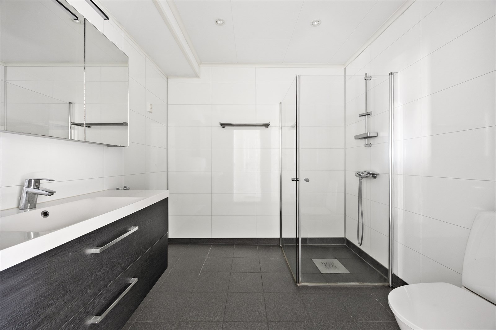 Badet i underetasjen har flislagt gulv, dusj på gulv og servantinnredning. Galleribilde