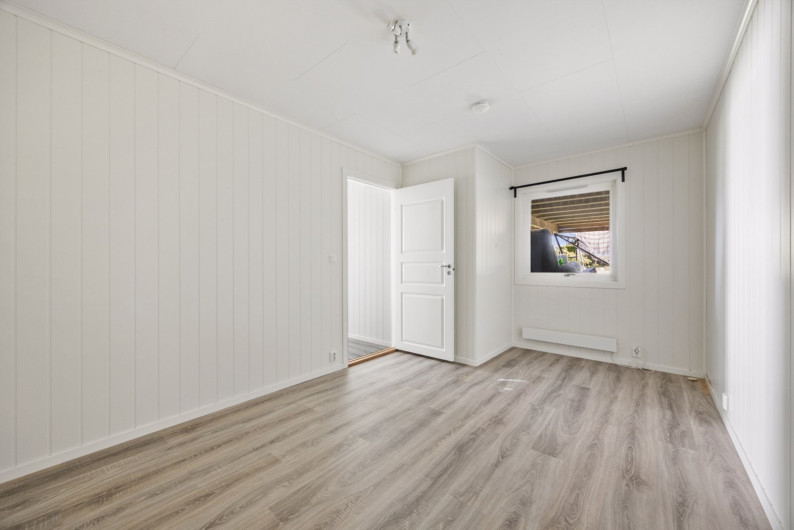 Rommet har panel på veggene og laminat på gulvet. Galleribilde
