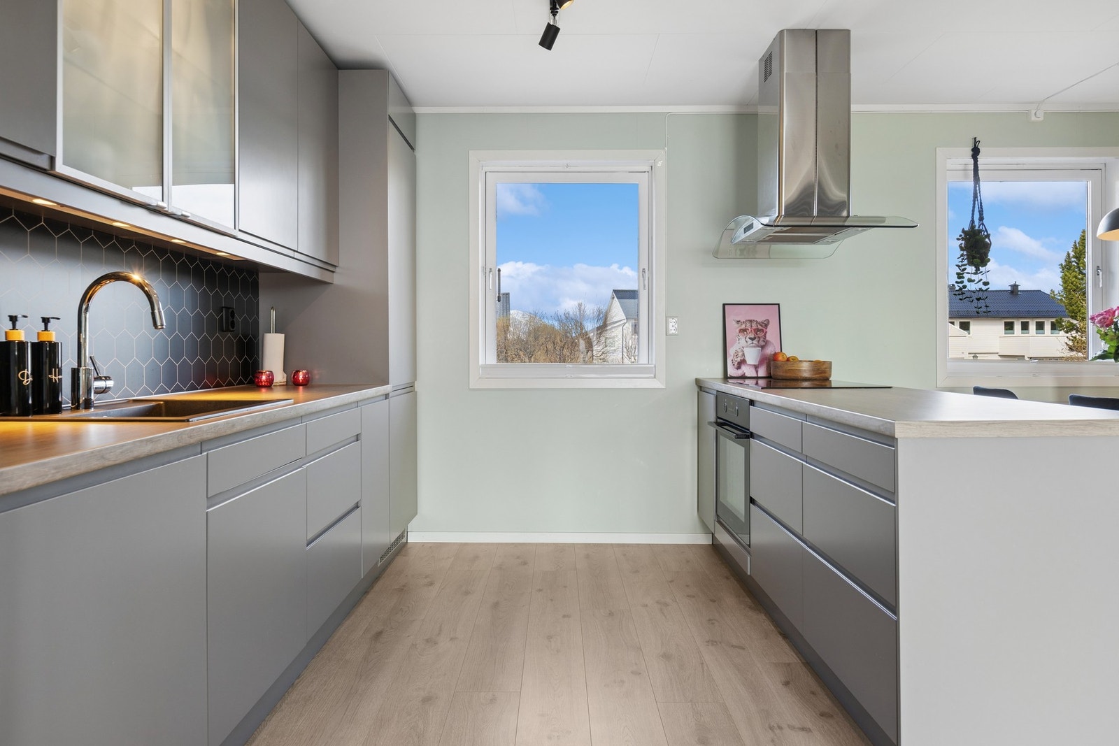 Moderne kjøkkeninnredning med slette, grå fronter og rikelig med skap- og benkeplass. Galleribilde