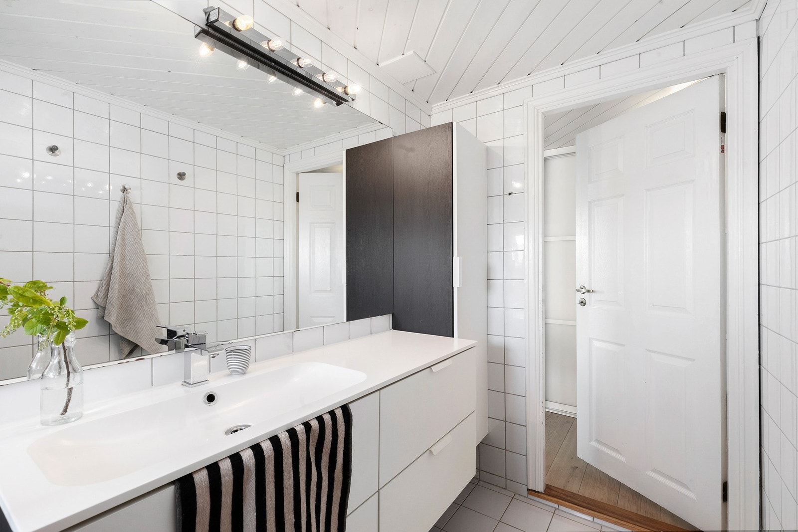 Badet er utstyrt med dusj, toalett og pen baderomsinnredning med servant. Galleribilde