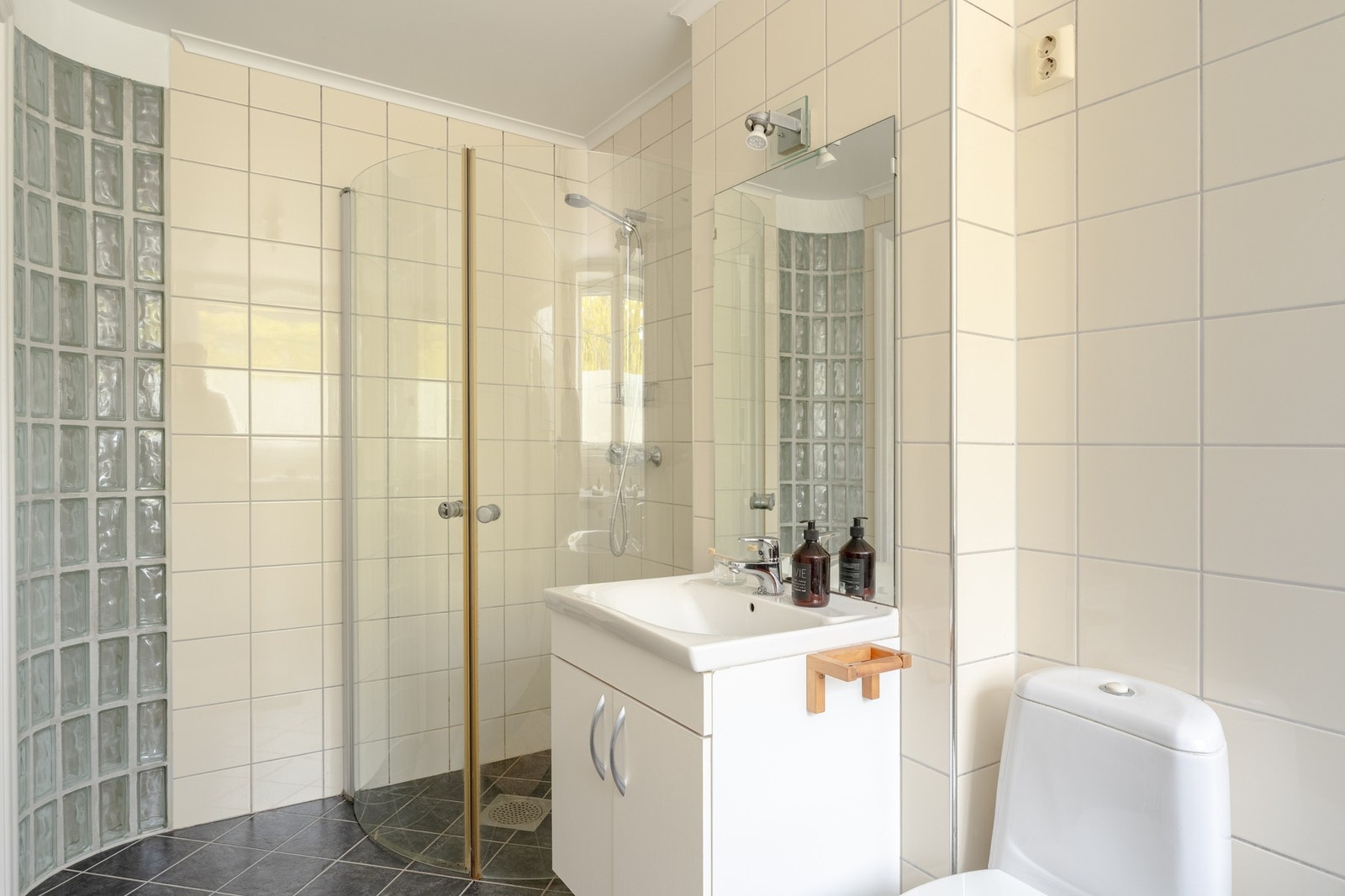 Badet er innredet med toalett, servant med innredning, dusjhjørne og opplegg for vaskemaskin. Galleribilde