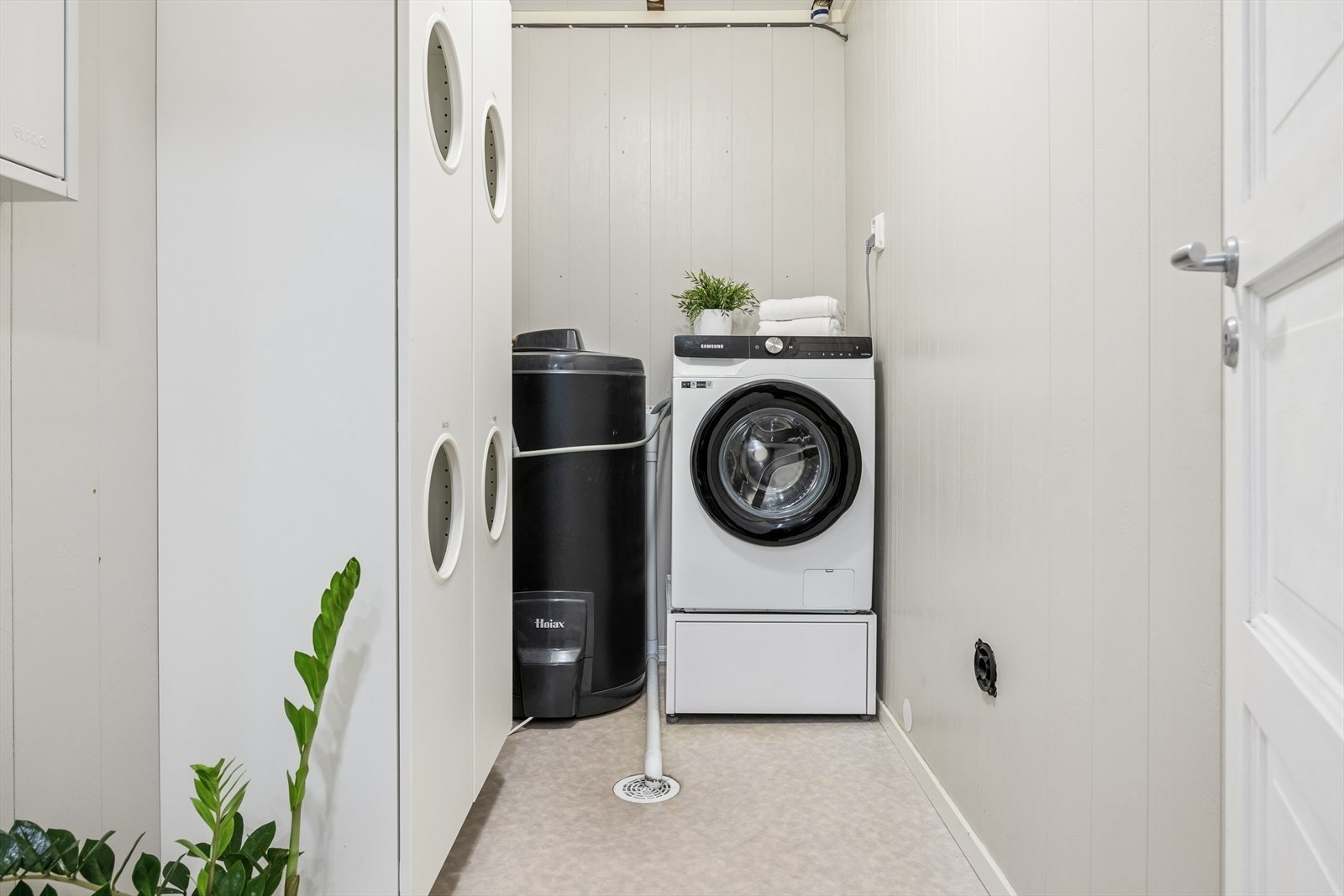 Inne på badet er det adkomst til bod, innredet som vaskerom med opplegg til vaskemaskin og gulv med belegg og sluk Galleribilde