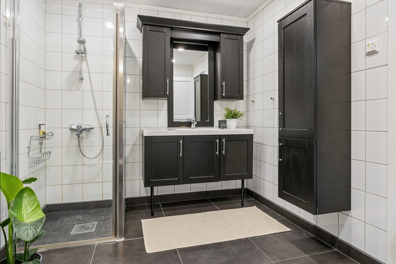 Badet er lyst og innbydende, med flislagte vegger i lyse toner og mørkere fliser på gulvet Galleribilde