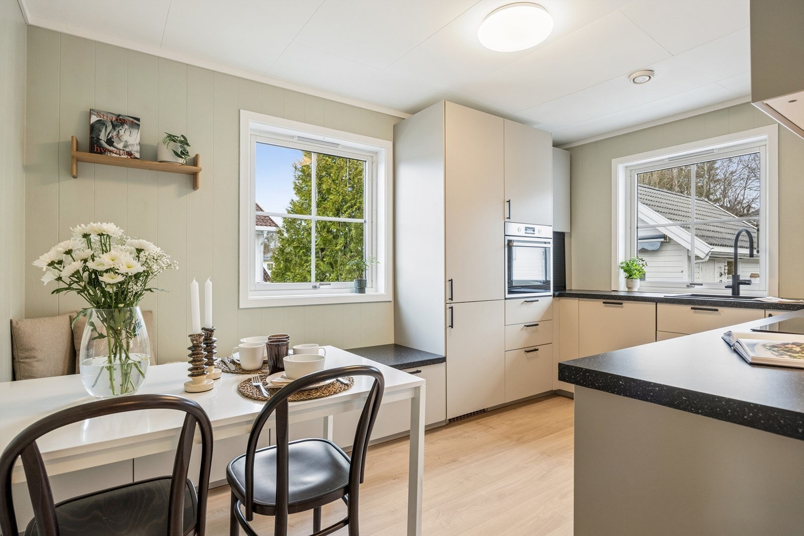 Kjøkkenet er nytt, moderne og smakfullt innredet i lyse, duse toner kombinert med stilrene sorte detaljer som gir et elegant og tidsriktig uttrykk. Innredningen har folierte, slette fronter som bidrar til et minimalistisk preg, og en laminert benkeplate Galleribilde