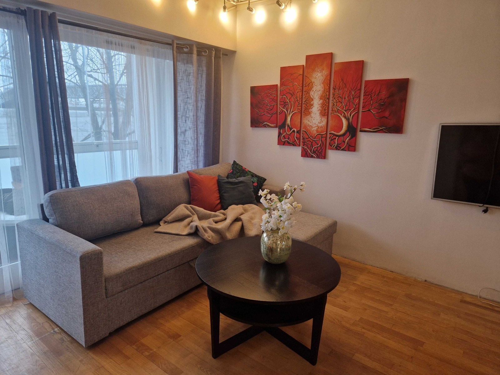 Stuen er møblert med bord og sovesofa og tv på veggen. Tven står på svingbar arm Galleribilde