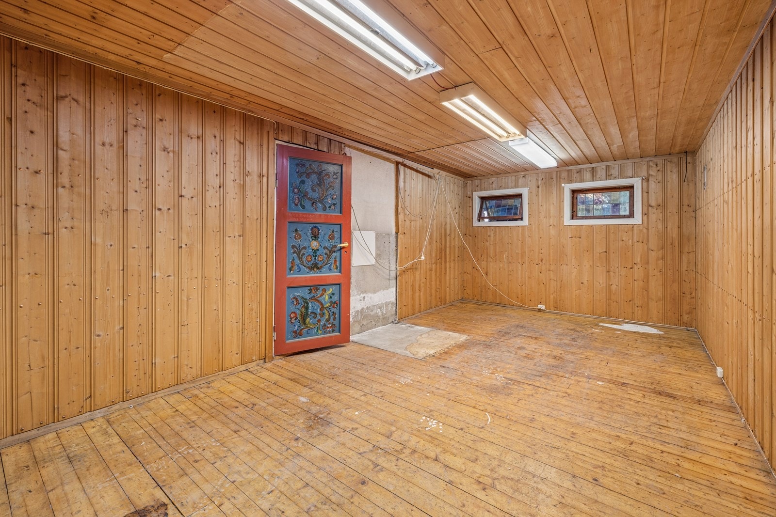 En av bodene i kjelleren, med panel på vegger og oppforet betongdekke med gulvbord. Galleribilde