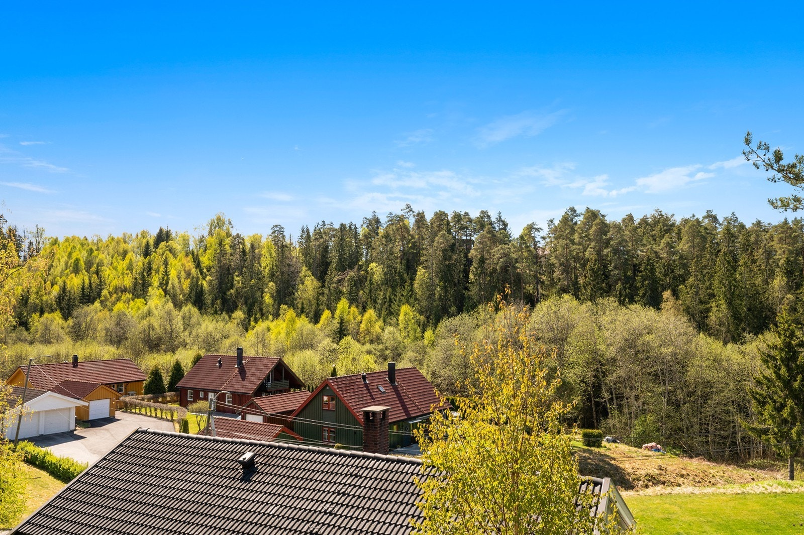 Utsikt over boligområde med skog i bakgrunnen, som gir en landlig og rolig atmosfære. Galleribilde