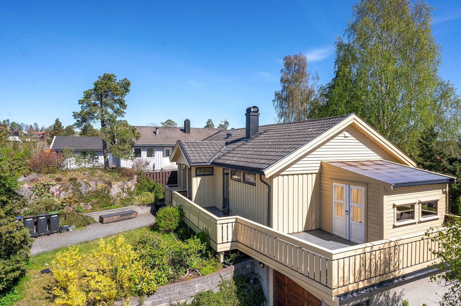 Tomten er svakt skrånende og opparbeidet med steinheller, plenarealer, støttemurer og beplantninger. Galleribilde