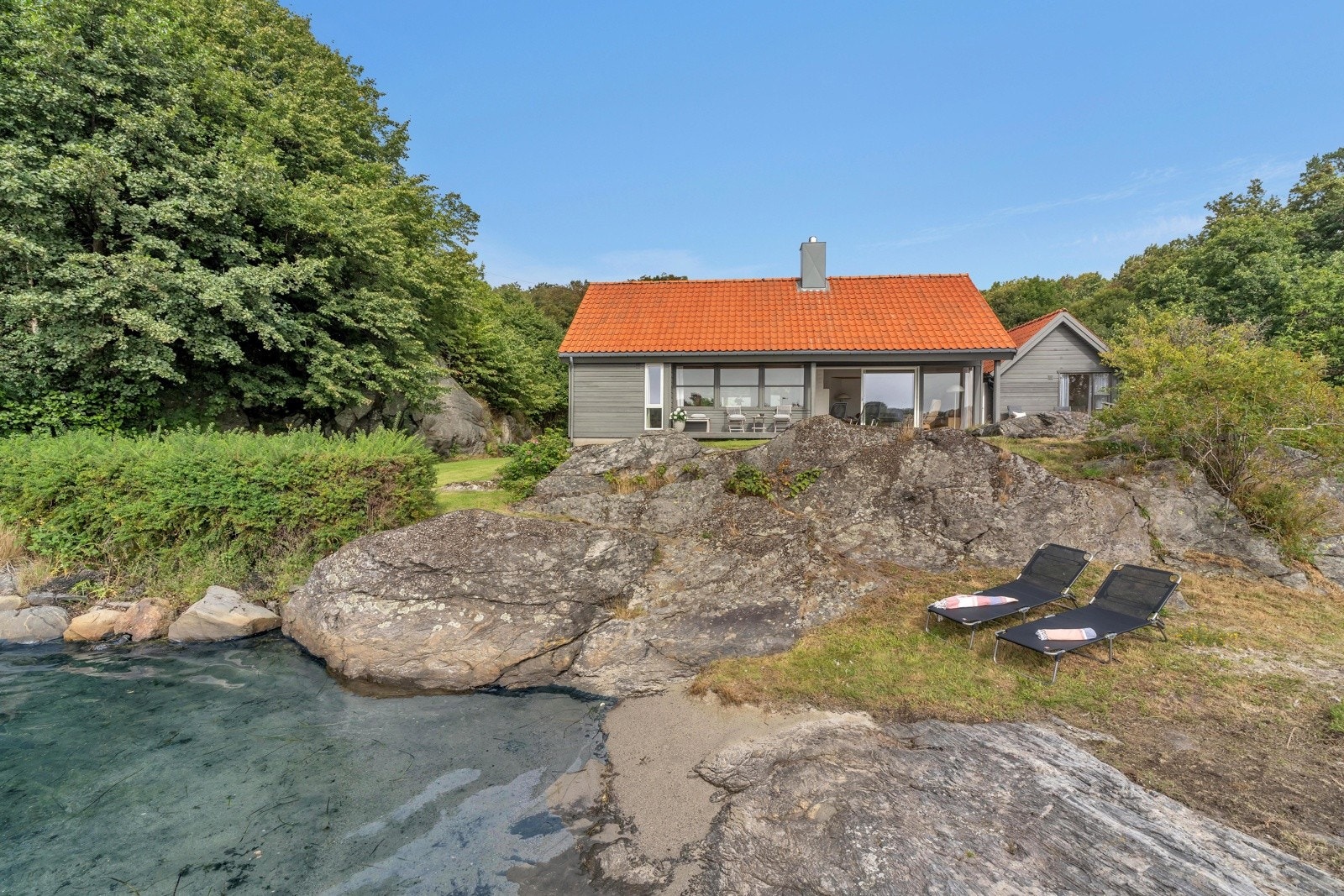 Lang strandlinje bestående av dypvannsbrygge, sandstrand og svaberg. Galleribilde