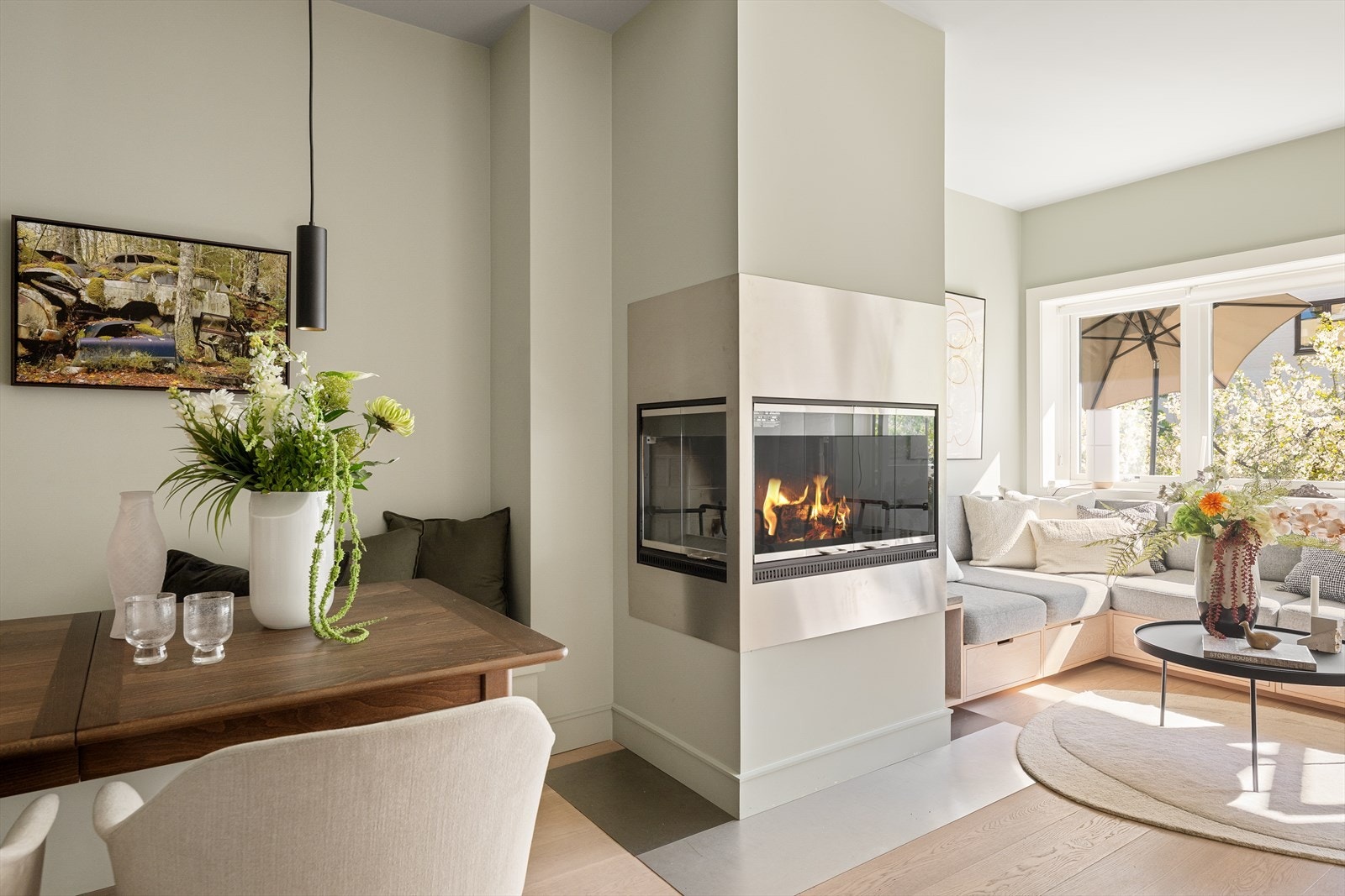 En elegant og moderne peis fungerer som et naturlig midtpunkt mellom spiseplass og sofagruppe. Galleribilde