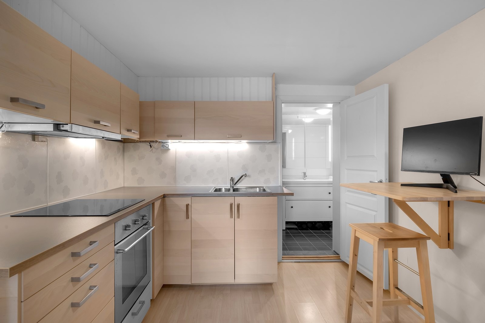 Kjøkkeninnredning av nyere dato med glatte fronter og laminat benkeplate, samt integrert koketopp og stekeovn. Galleribilde