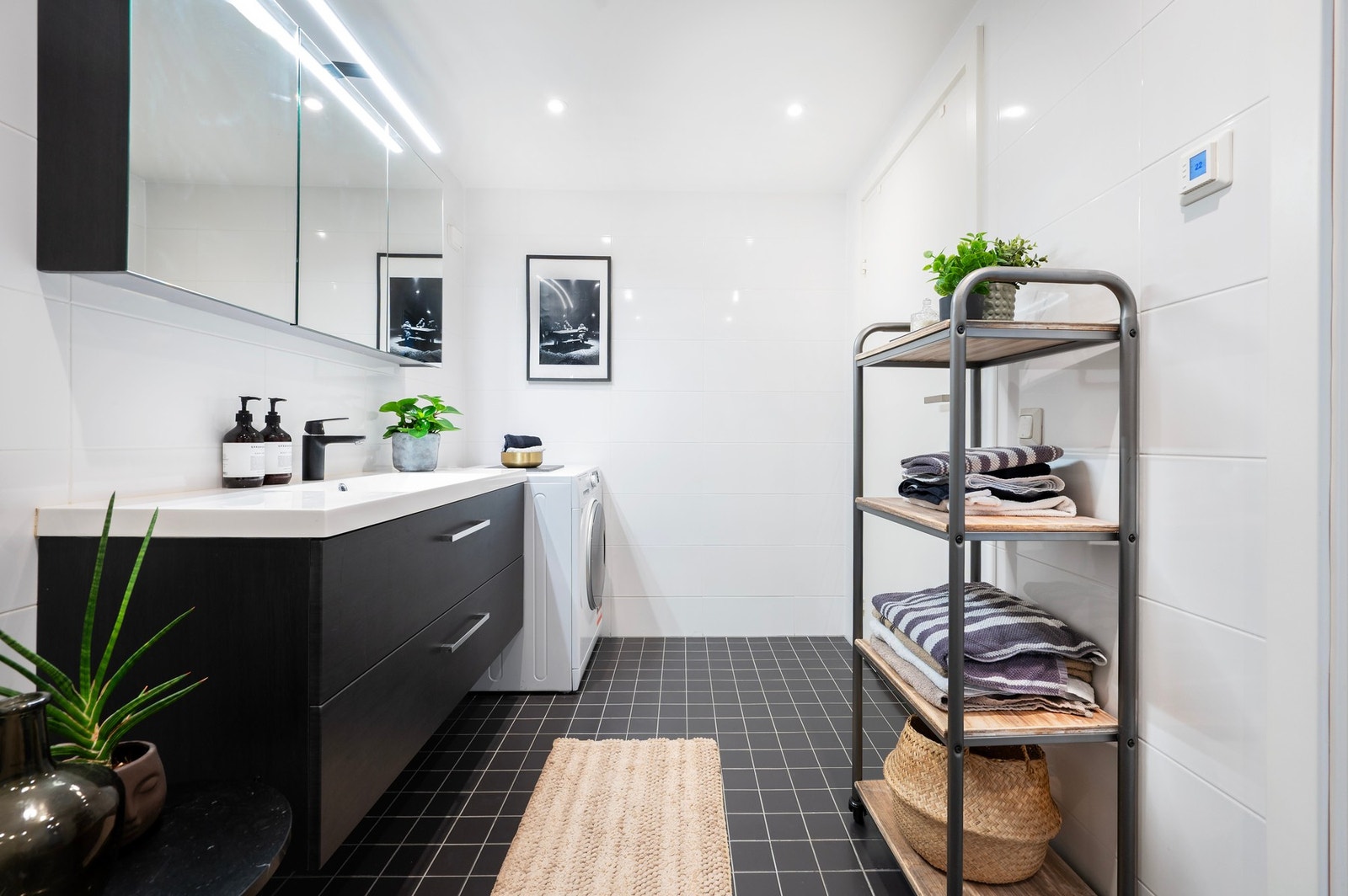 Badet er innredet med nedfelt servant, veggmontert toalett, dusjvegger/hjørne og med opplegg for vaskemasin/tørketrommel. Galleribilde