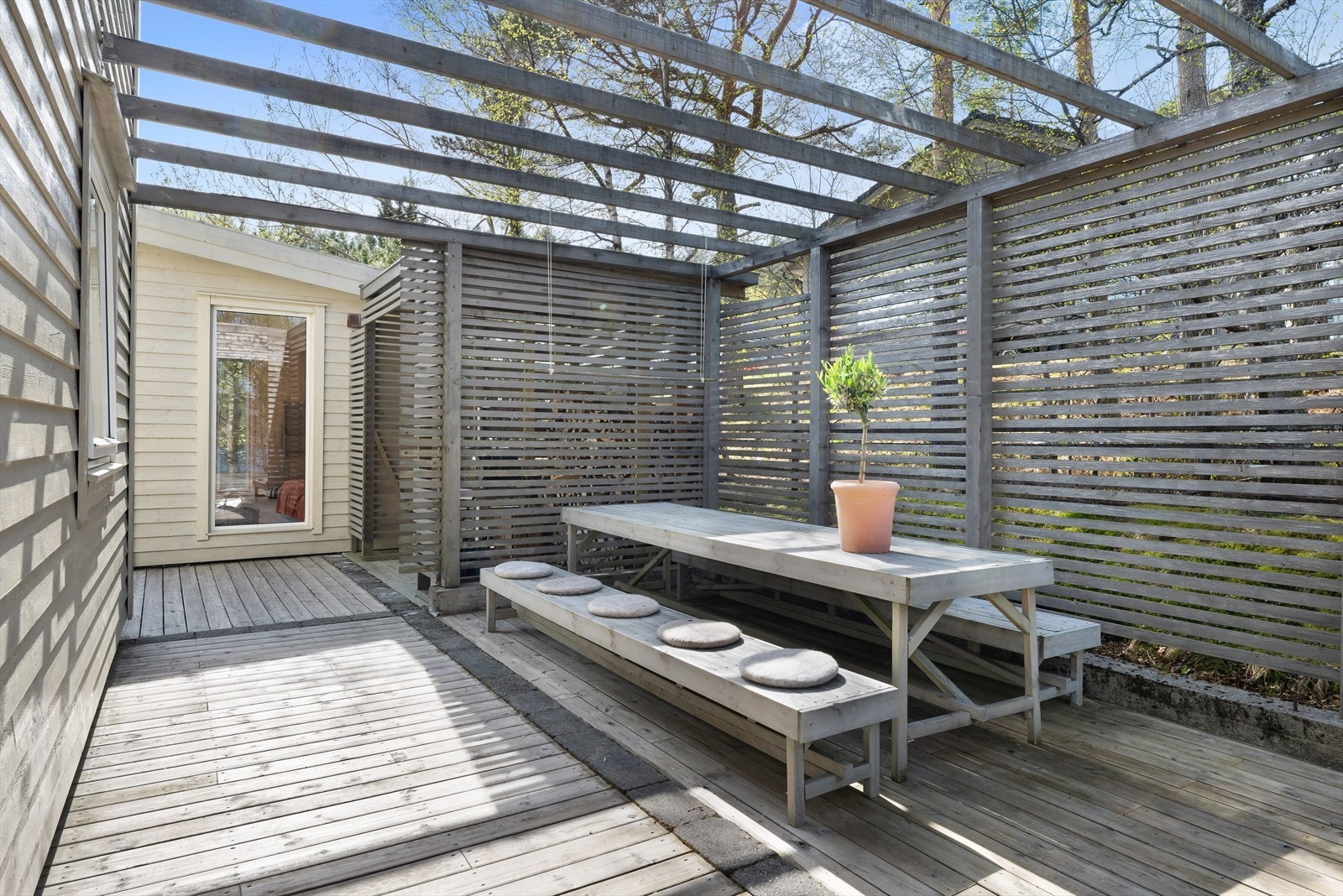 En skjermet uteplass med pergola skaper en lun og privat sone på terrassen på nordsiden av huset. Galleribilde