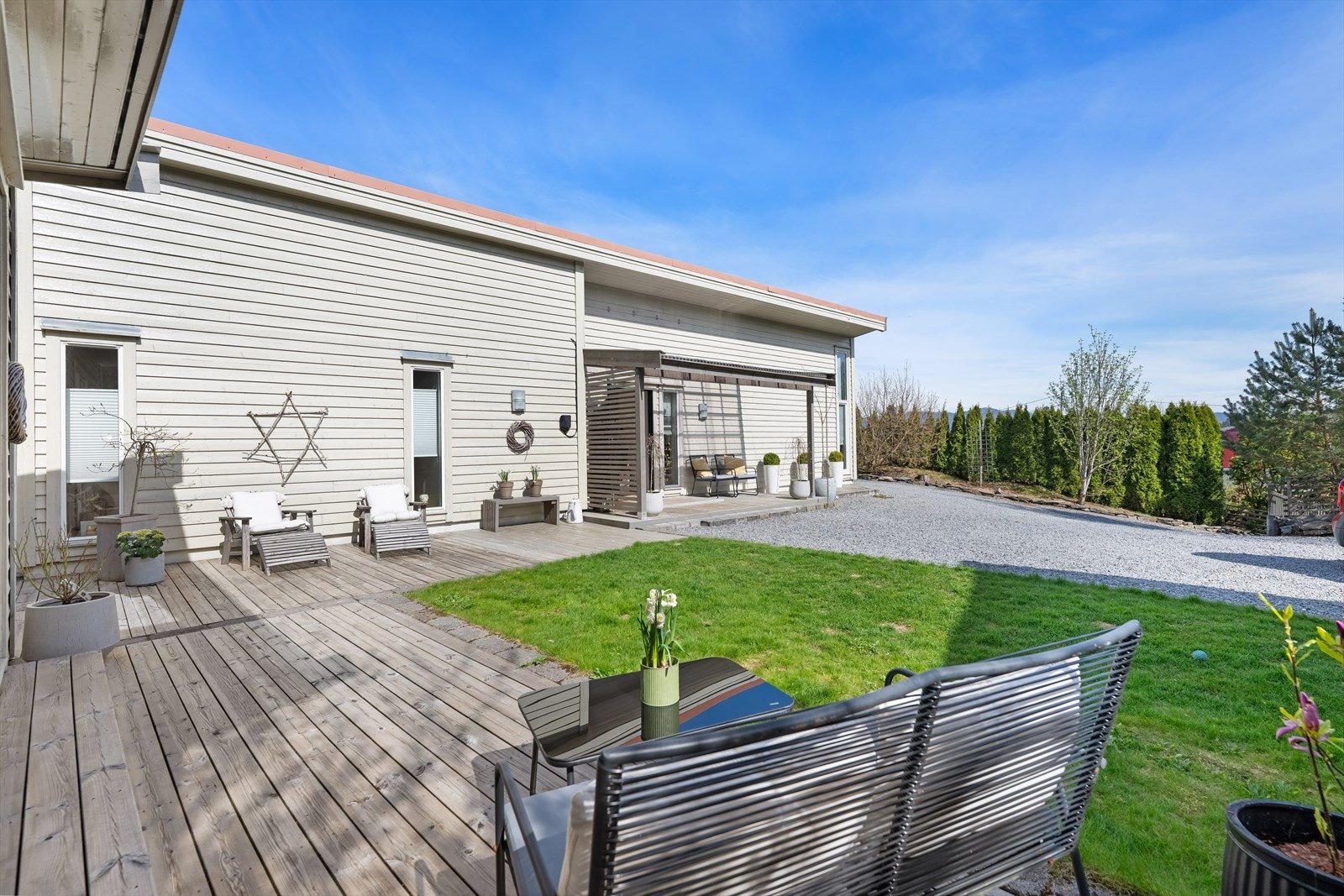Tomten er pent opparbeidet med gruslagt gårdsplass, plen og store terrasseområder. Galleribilde