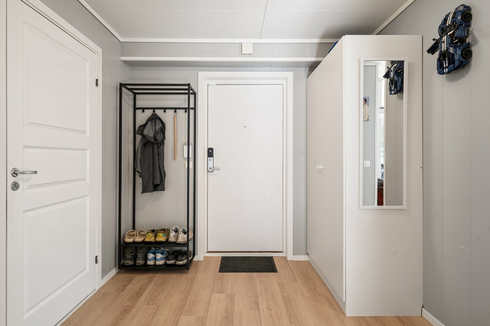 Velkommen inn i en praktisk og oversiktlig entré med god plass til yttertøy og sko. Rommet har funksjonell garderobeløsning, garderobeskap og speil som gir gode oppbevaringsmuligheter og en luftig romfølelse. Galleribilde
