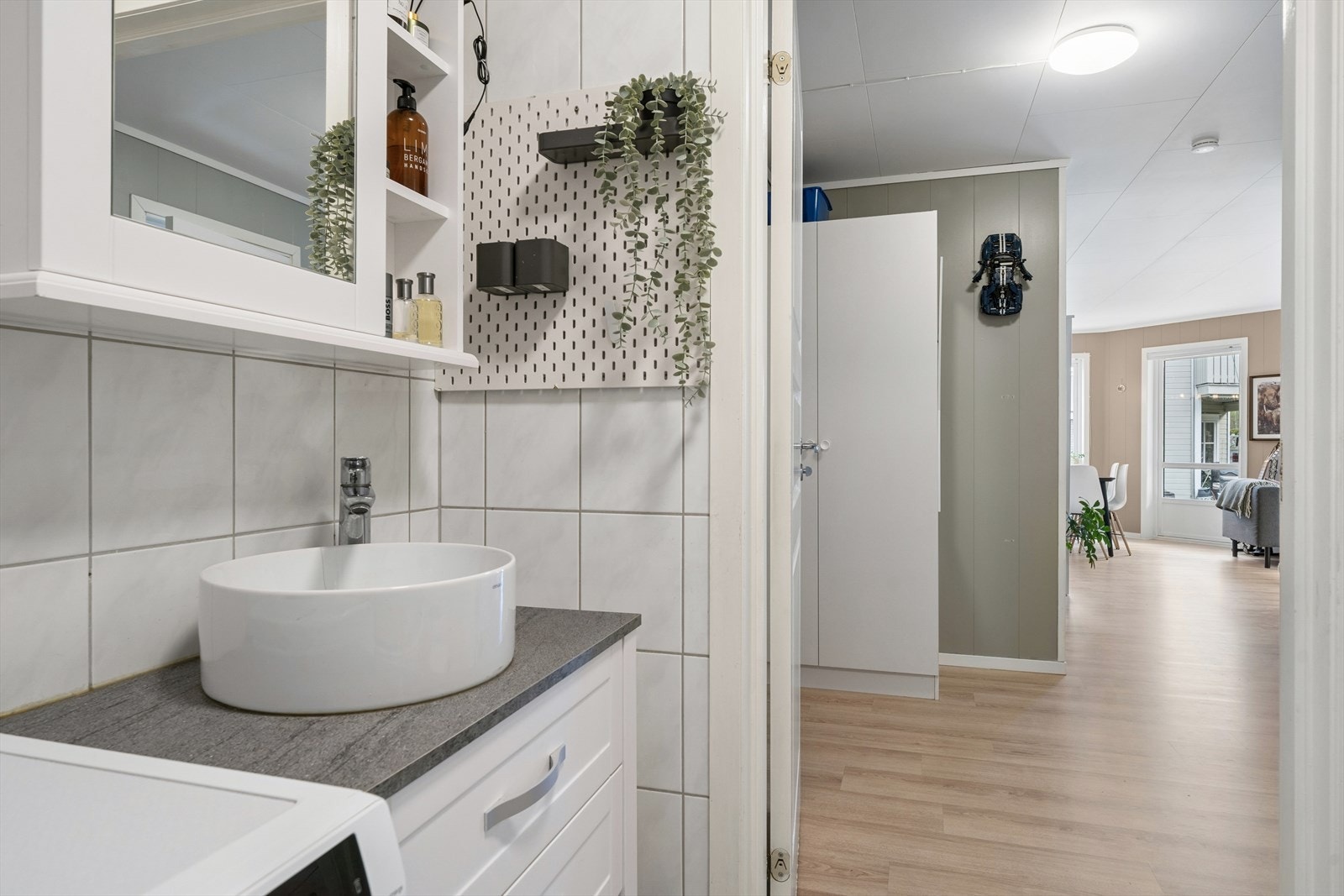 Stilrent baderom med moderne servantløsning og praktisk speilskap som gir ekstra oppbevaring. Flislagte overflater i lyse, nøytrale toner skaper et rent og tidløst uttrykk. Galleribilde