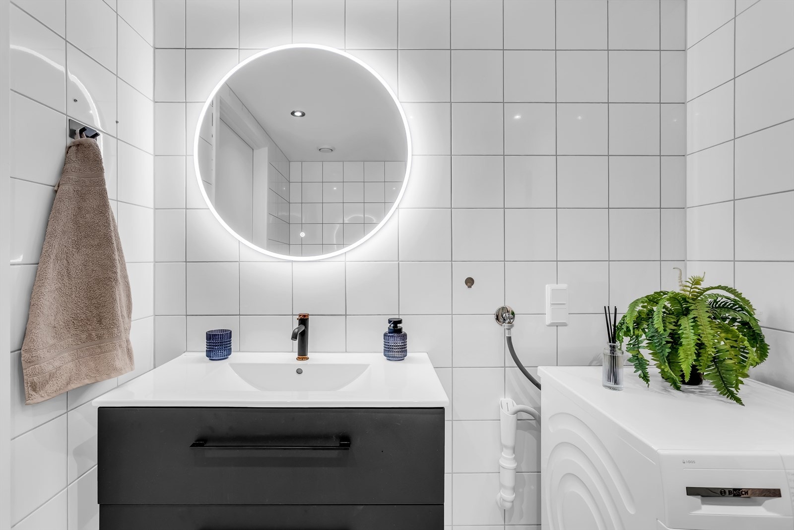 Baderomsinnredningen har glatte, mørke fronter og servant med ettgreps blandebatteri. Speilet har integrert belysning. Galleribilde