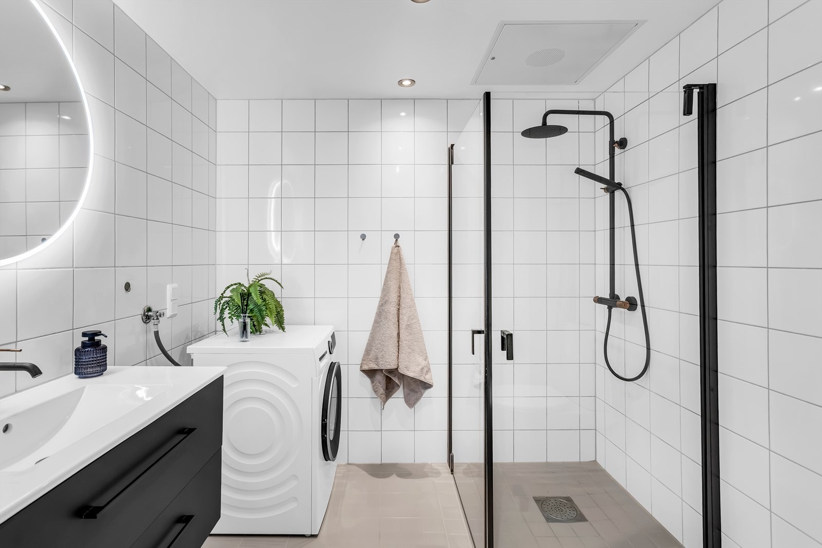 Flislagt bad med elektrisk gulvvarme. Innredning, dusjløsning og armaturer er oppgradert med moderne, sorte detaljer. Galleribilde