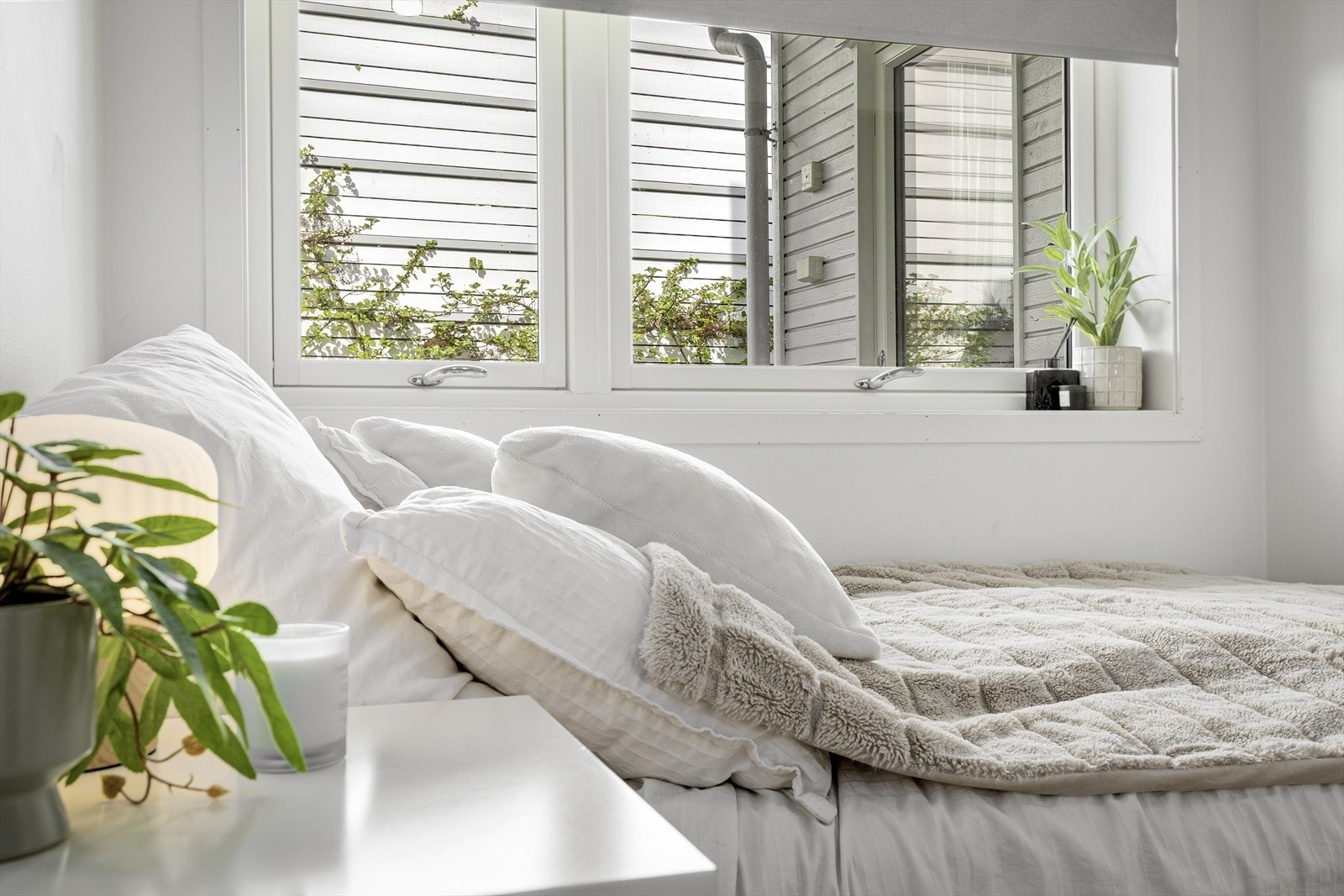 Soverom med store vindaugsflater som slepp inn godt med naturleg lys. Vindauga vender mot skjerma fasade som gir eit roleg og privat preg på rommet. Galleribilde