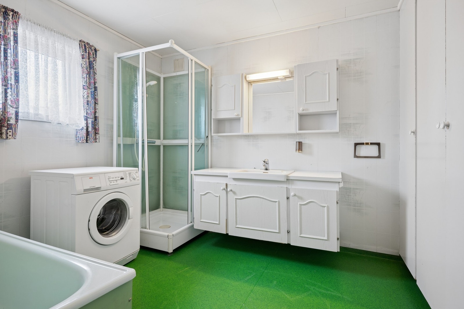 Badet har gulvvarme og er utstyrt med badekar, dusjkabinett og opplegg for vaskemaskin. Galleribilde