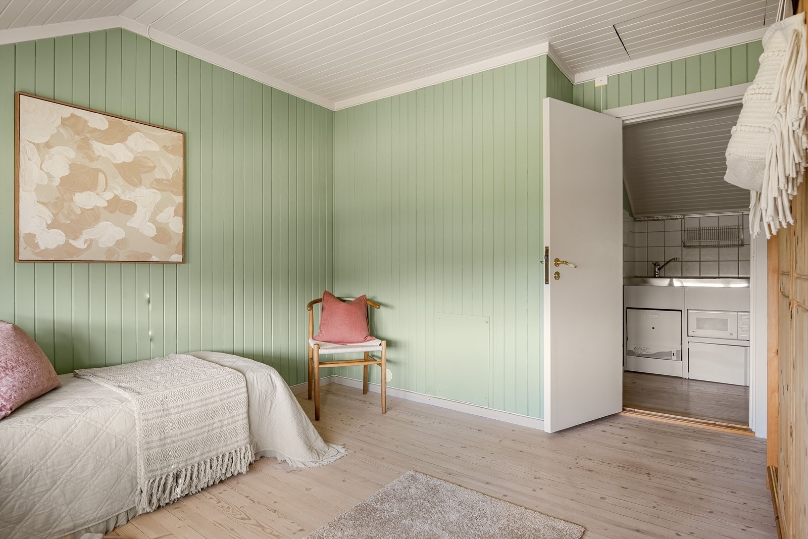 Soverommet har lyse tregulv og panel på veggene malt i en fin grønnfarge. Galleribilde