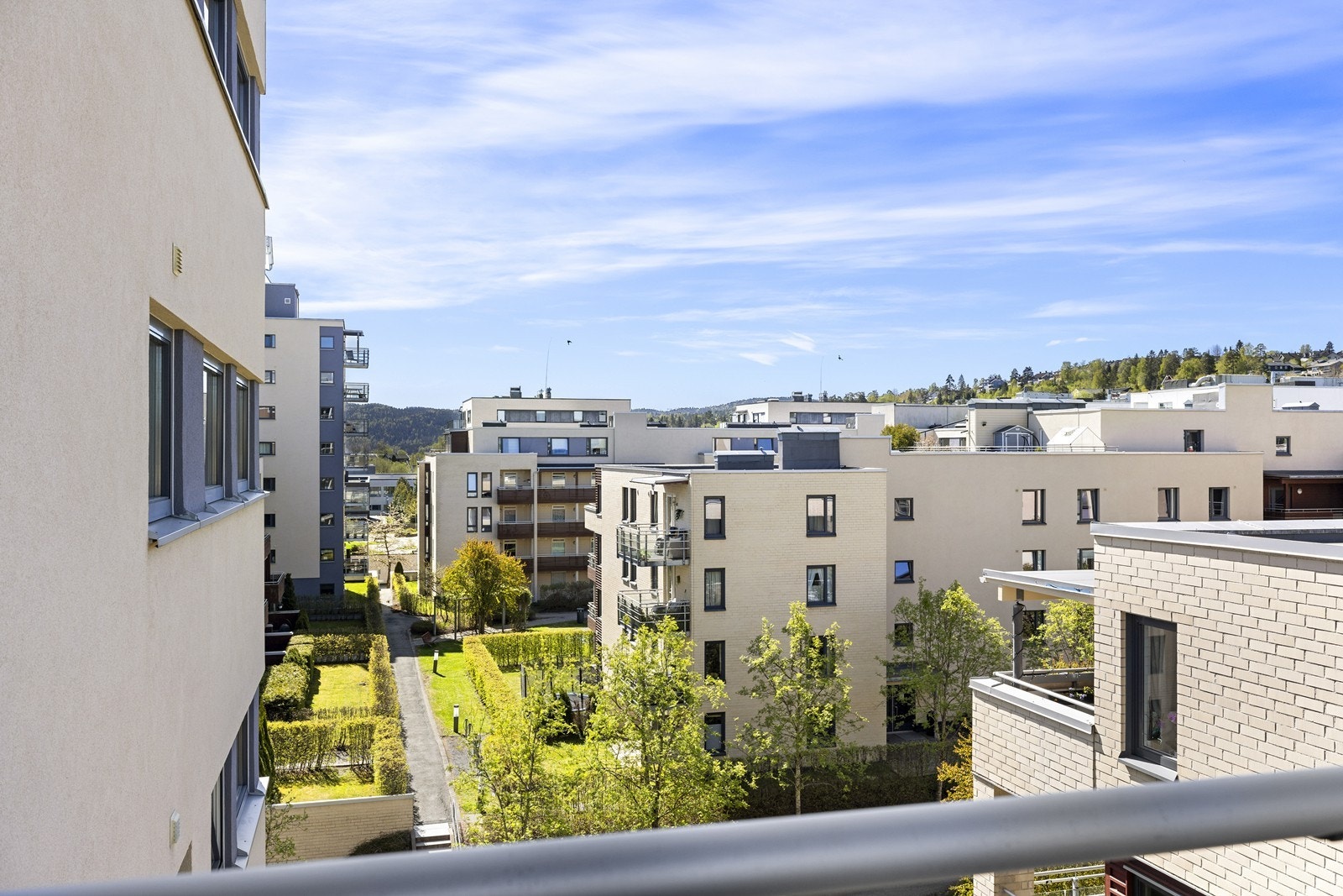 Fra 5. etasje har du utsyn over et rolig og etablert nabolag med pent opparbeidede fellesarealer. Galleribilde
