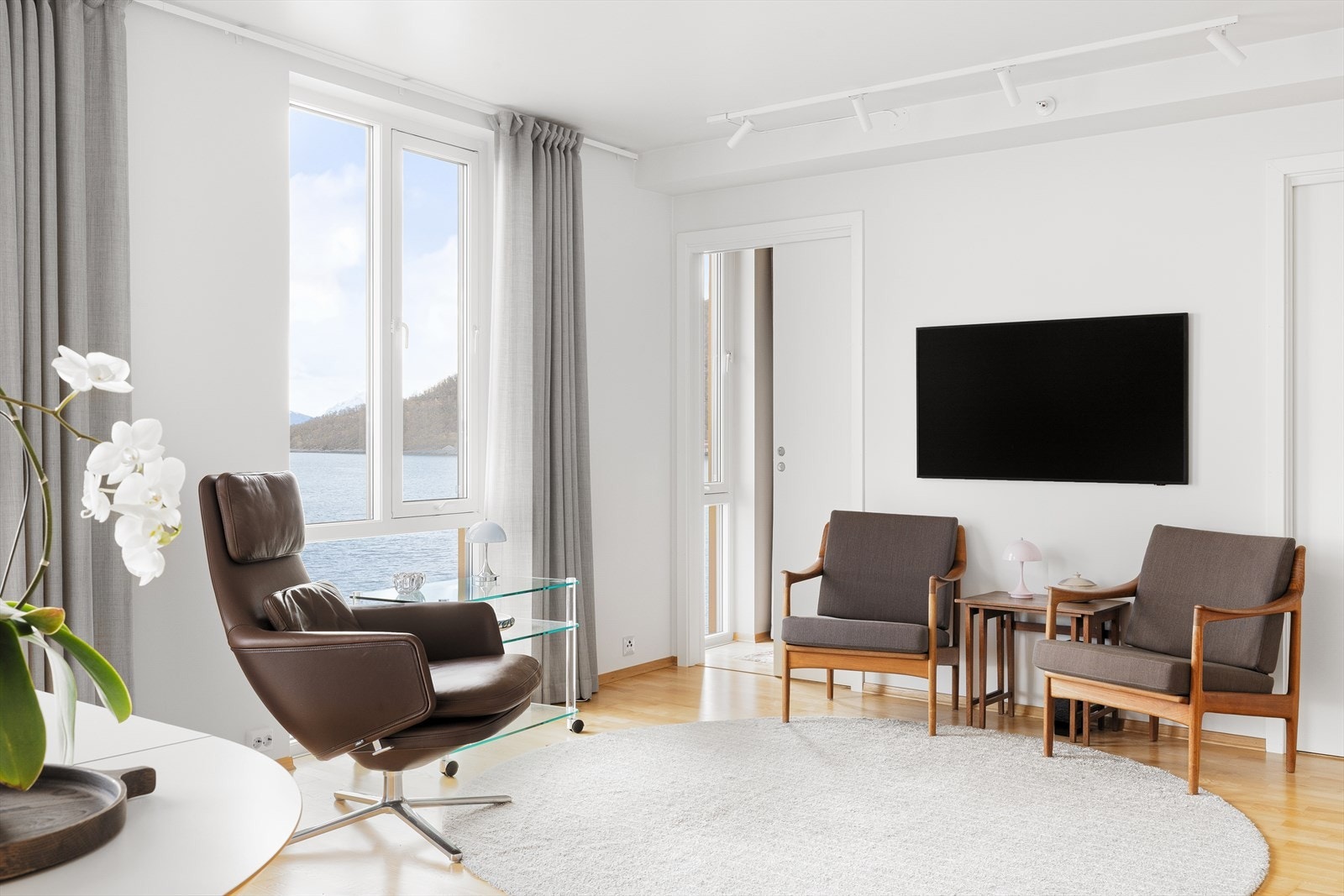 De store vindusflatene og den brede skyvedøren ut til balkongen slipper inn rikelig med naturlig lys gjennom hele dagen og skaper en lys, åpen og innbydende atmosfære i stuen. Galleribilde