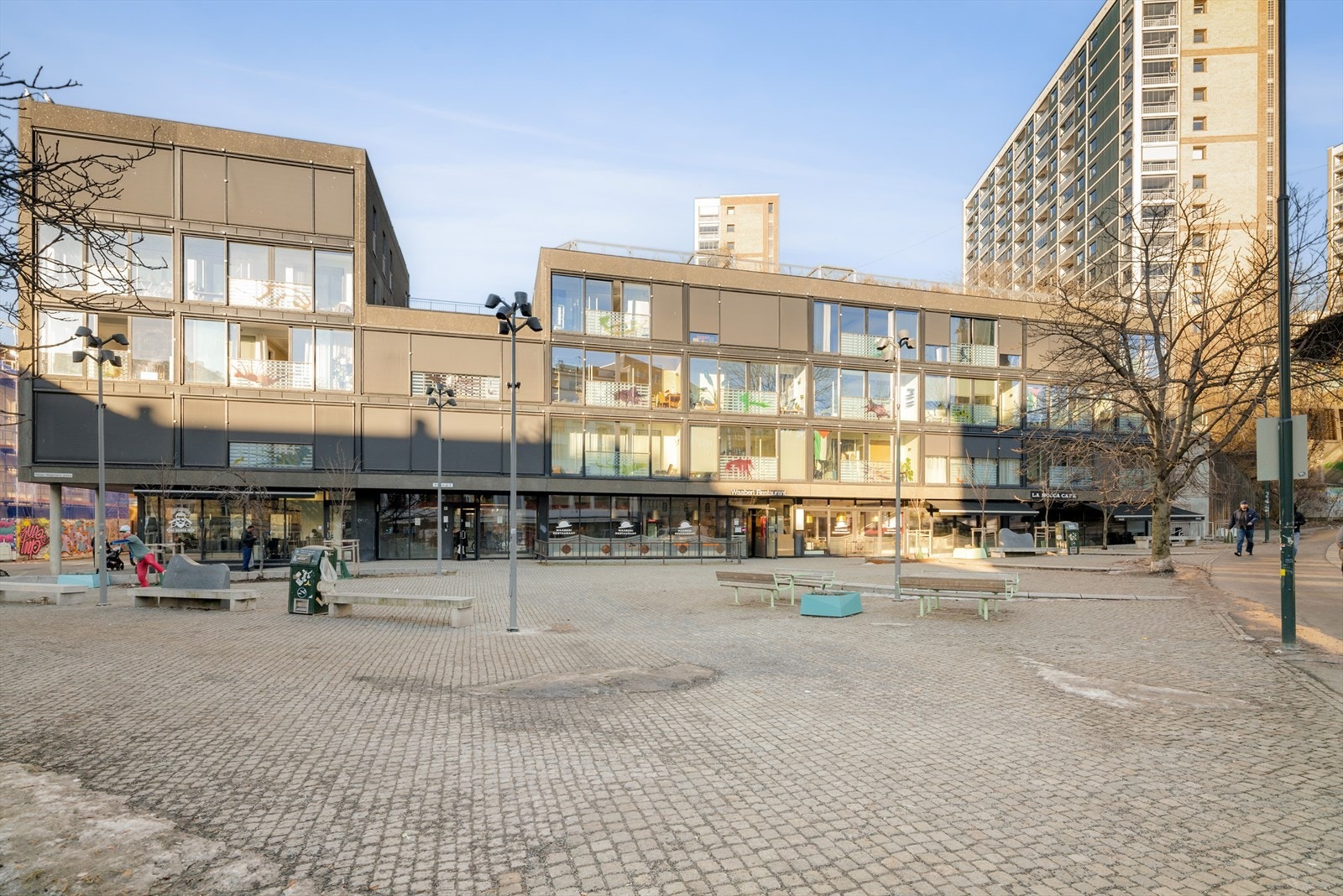 Helga Helgesens plass er vakkert etablert med brosten, tuntrær, kunstnerisk fontene, trivelige sittebenker og rekker av kirsebærtrær. Galleribilde