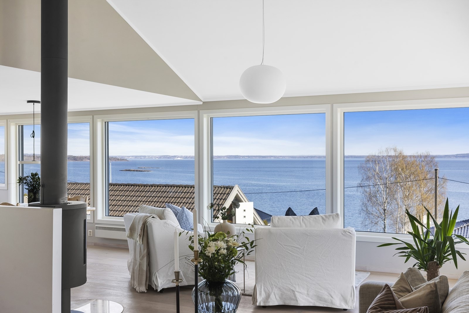 Stuen er boligens hjerte, med imponerende takhøyde og store vindusflater som slipper inn rikelig med naturlig lys og rammer inn fjordutsikten. Galleribilde