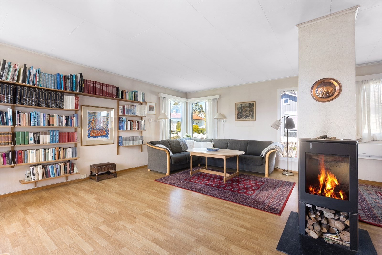 Stuen har laminatgulv og god plass til møblering i ulike soner. Vedovnen gir lun varme. Galleribilde