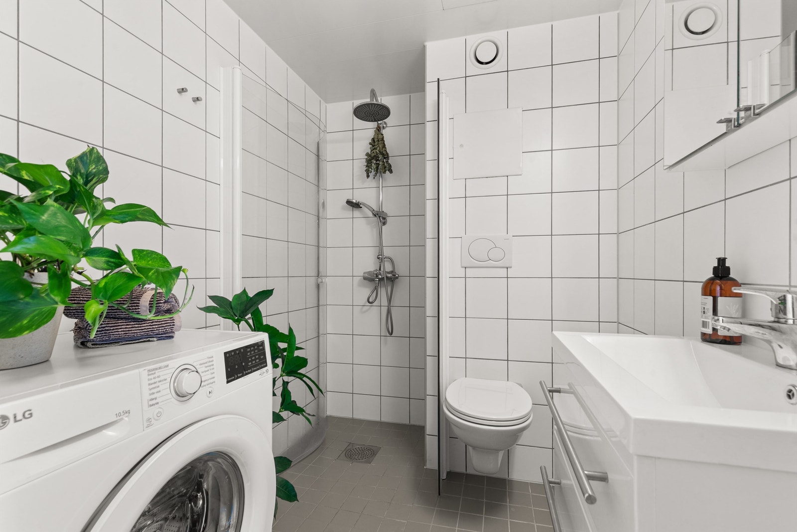 Badet har flislagte overflater med elektrisk gulvvarme for økt komfort. Innredningen består av et vegghengt klosett, servant nedfelt i innredningen og et praktisk speilskap med belysning. Galleribilde