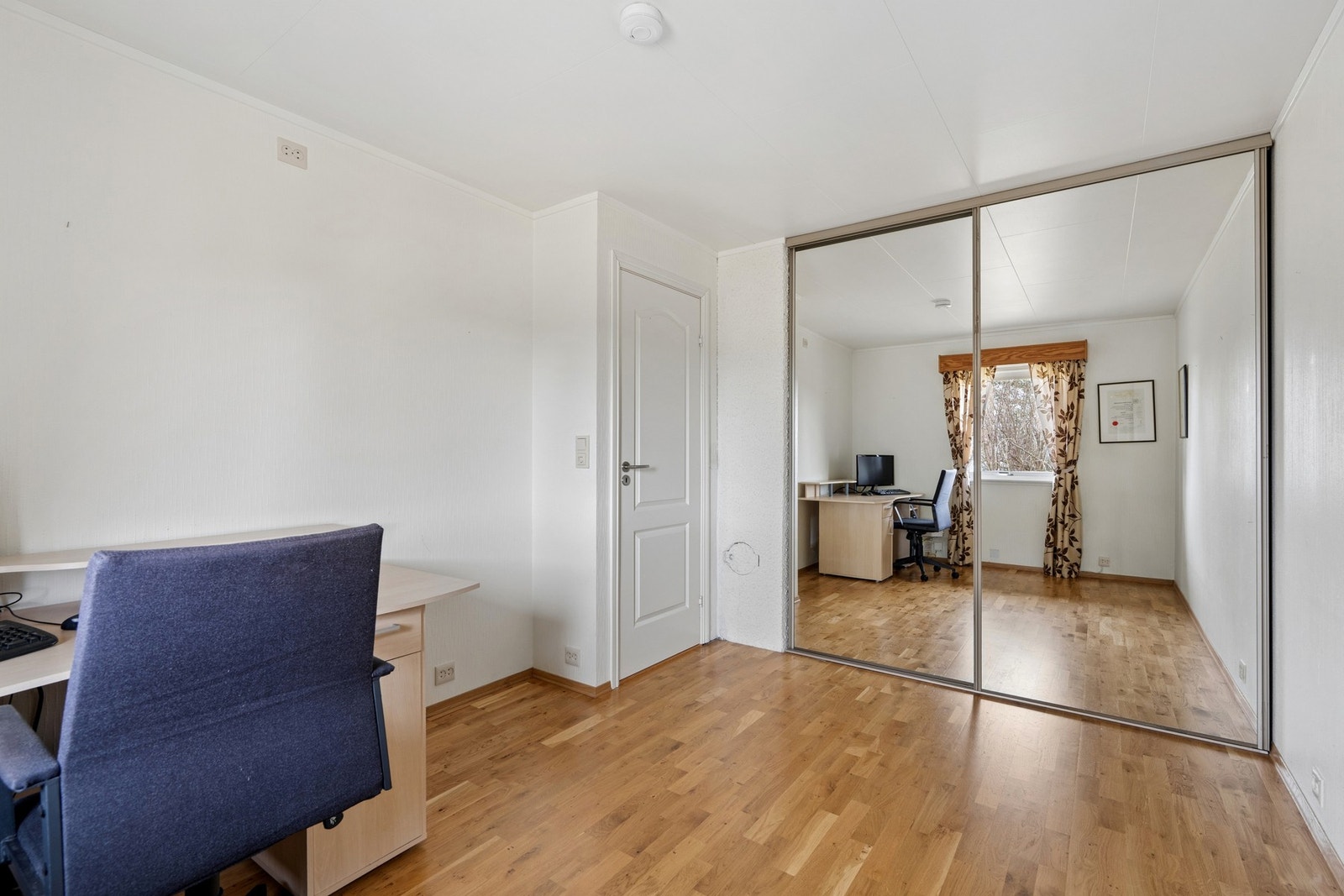 En romslig skyvedørsgarderobe med speilfronter gir rikelig med oppbevaringsplass. Galleribilde