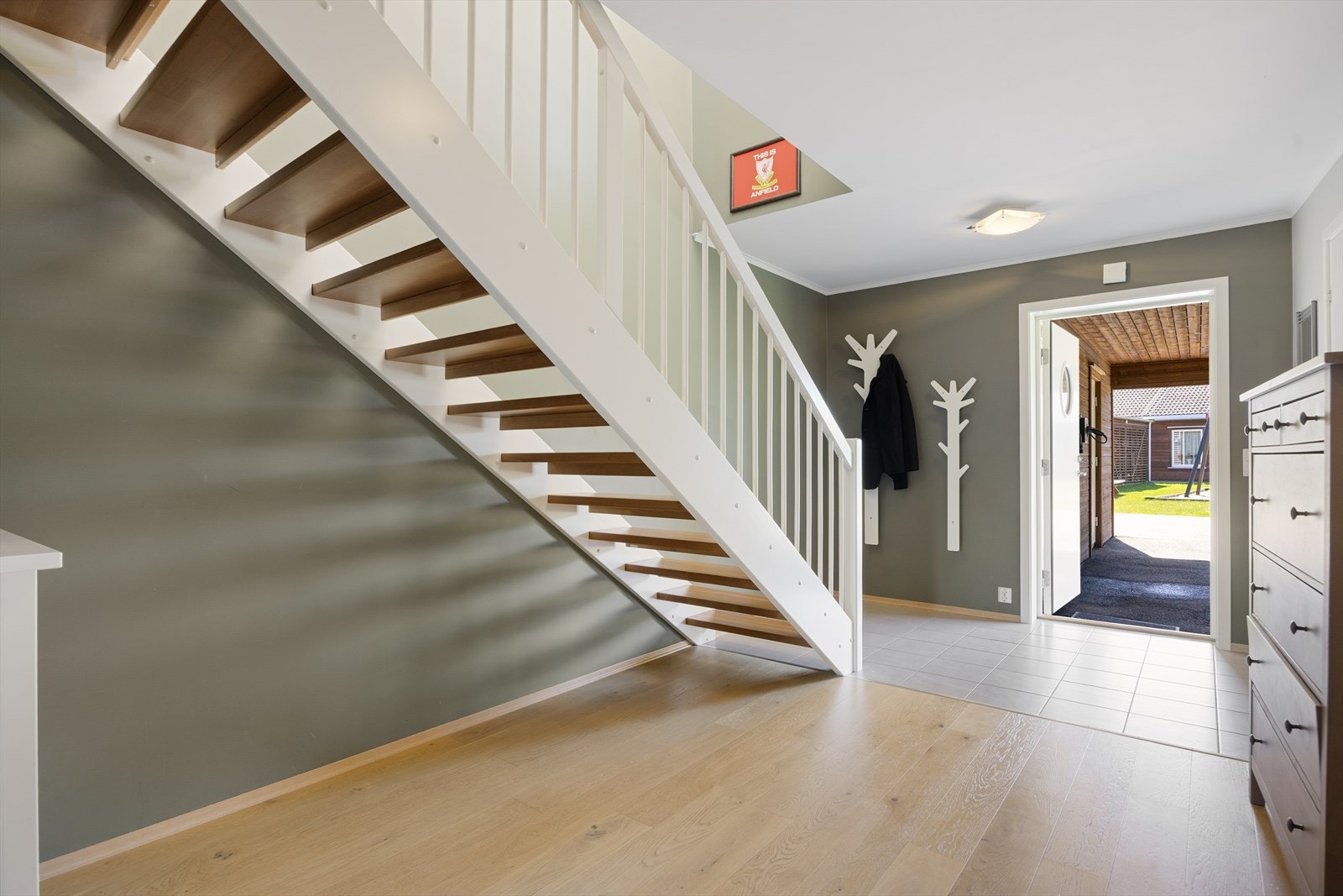 Hallen har flislagt gulv ved inngangen og parkett videre innover. Trappen er en malt tretrapp med lakkerte trinn. Galleribilde