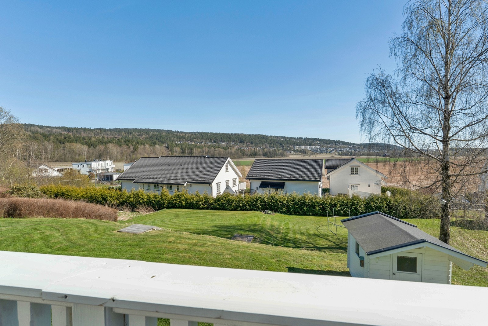 Fra terrassen er det utsikt over hagen og nærområdet, som inkluderer gressplen og beplantning. Galleribilde