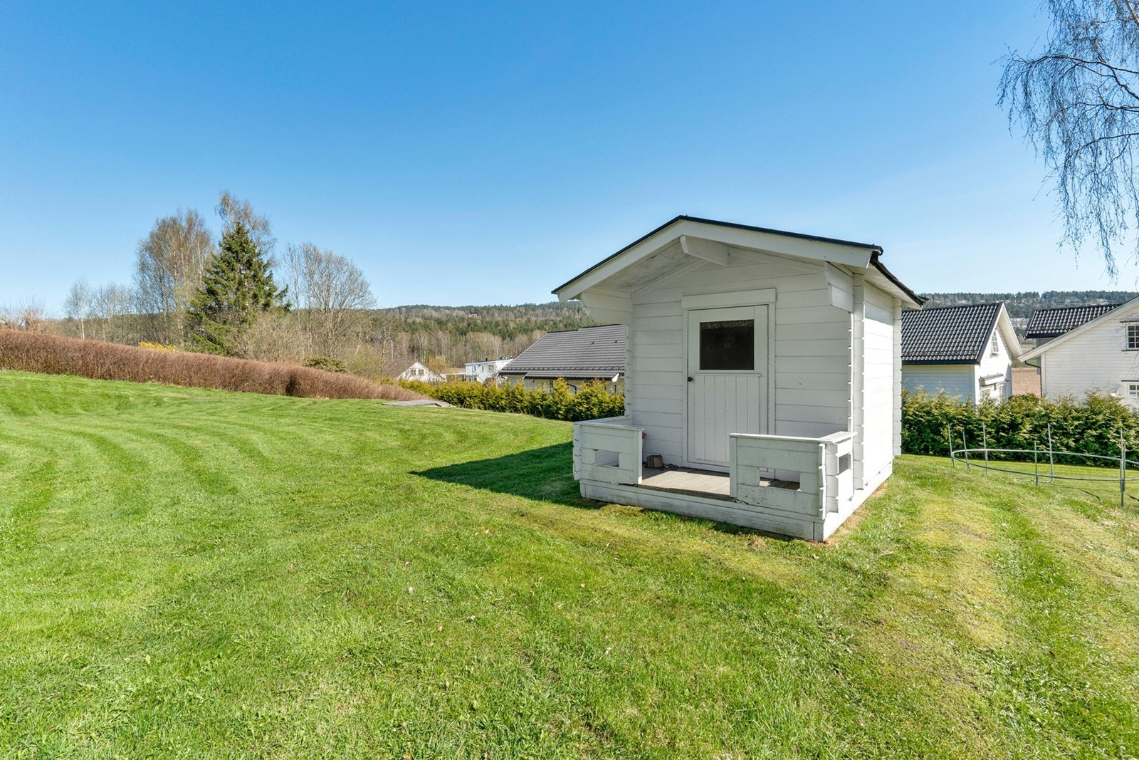 Tomten er pent opparbeidet med plen og prydbusker, og inkluderer en sjarmerende lekestue. Galleribilde