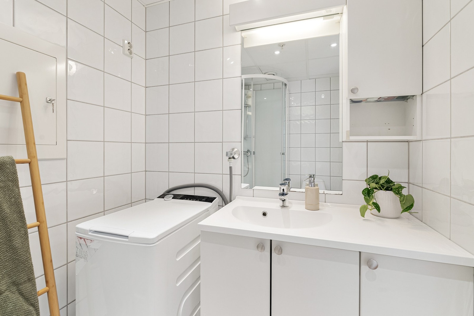 Servantinnredning med underskap, overskap og speil med lys ovenfor. Galleribilde
