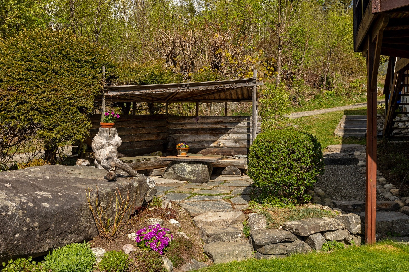 Skjermet og stemningsfull uteplass i hagen - et idyllisk område med naturstein, beplantning og lune soner for avslapning. Galleribilde