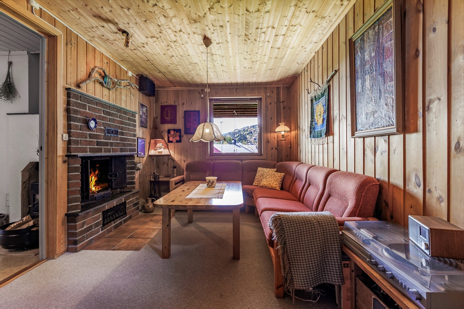 Stemningsfull kjellerstue med peis og lune treoverflater som gir en varm og hyggelig atmosfære - et perfekt rom for avslapning og sosiale kvelder. Galleribilde