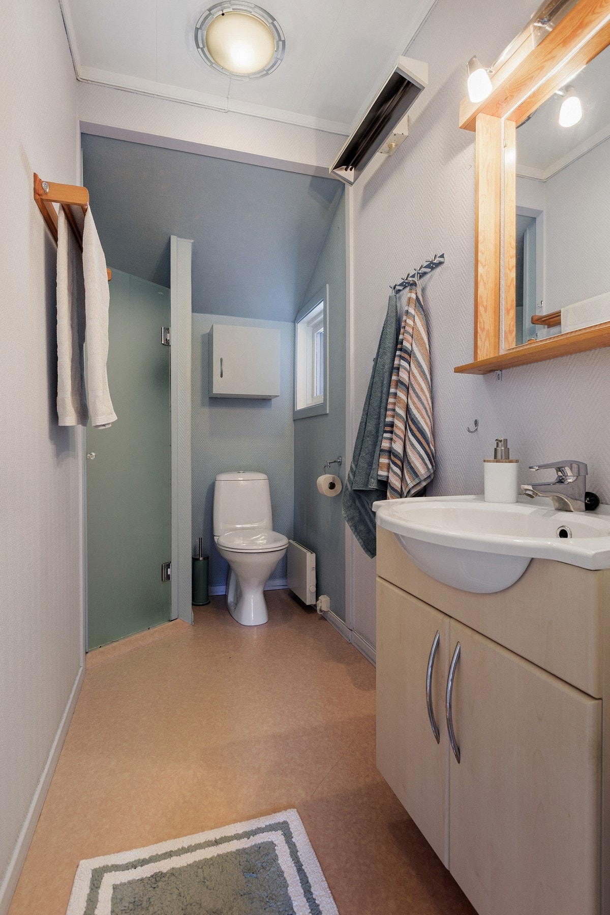 Praktisk bad med dusjløsning, servant med oppbevaring og lyse overflater som gir et rent og tidløst uttrykk. Galleribilde