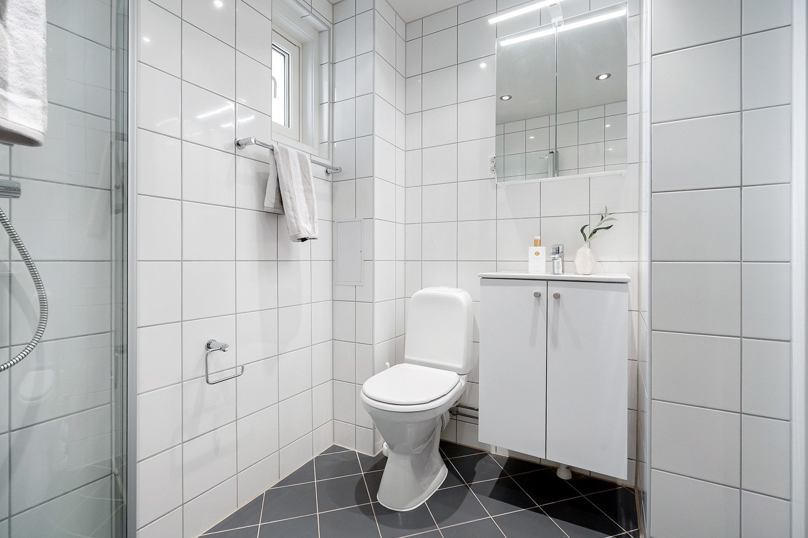 Pen baderomsinnredning med dusjhjørne med inn-/utadslående dusjvegger, ny servant med nytt underskap, nytt speilskap med lys over og nytt blandebatteri. Toalett og opplegg til vaskemaskin. Galleribilde