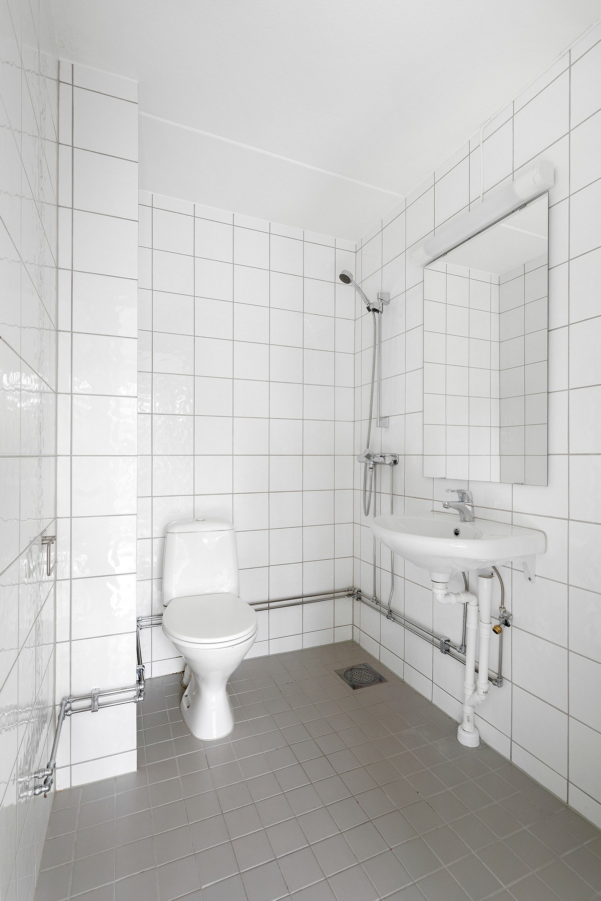 Badet er flislagt med dusj, wc, servant og opplegg for vaskemaskin Galleribilde