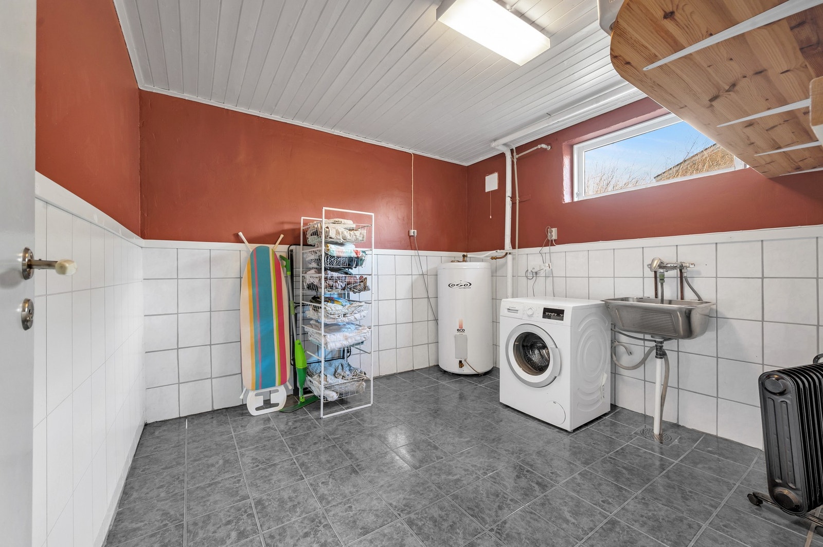 Romslig vaskerom i kjelleren med flislagt gulv, opplegg for vaskemaskin og plassering av varmtvannsbereder. Foto: H5 Galleribilde