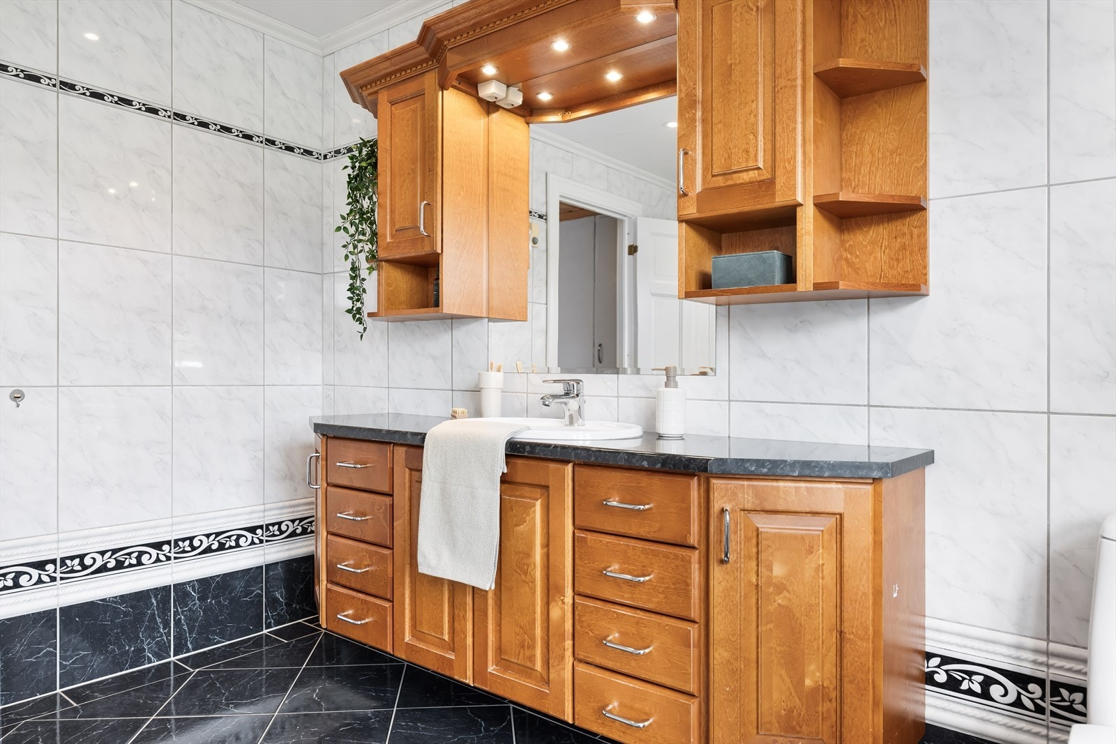 Baderomsinnredningen er i heltre og av god størrelse. Her får en plass til det meste. Rommets belysning, er som i det meste av boligen, fra downlights. Galleribilde