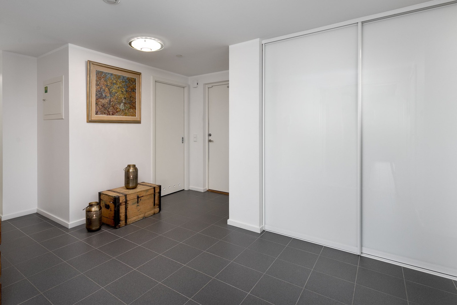 Flott entrè/hall med fliser på gulv og lysmalte overflater. Stor skyvedørsgarderobe. Galleribilde