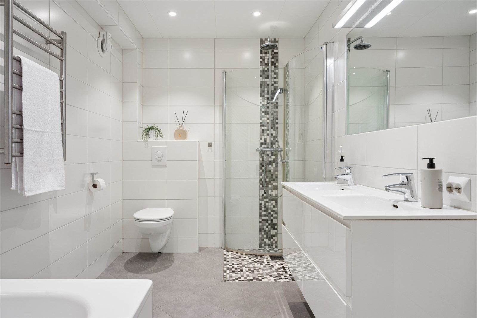 Badet har elektriske varmekabler i gulvet, vegghengt toalett og en servant med dobbel vask. Galleribilde