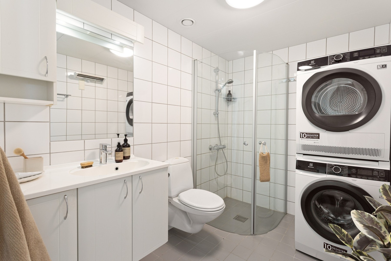 Boligen har et lyst bad med inngang fra entréen. Badet er bygget opp med hvite fliser på vegg og grå fliser på gulv med gulvvarme. Galleribilde
