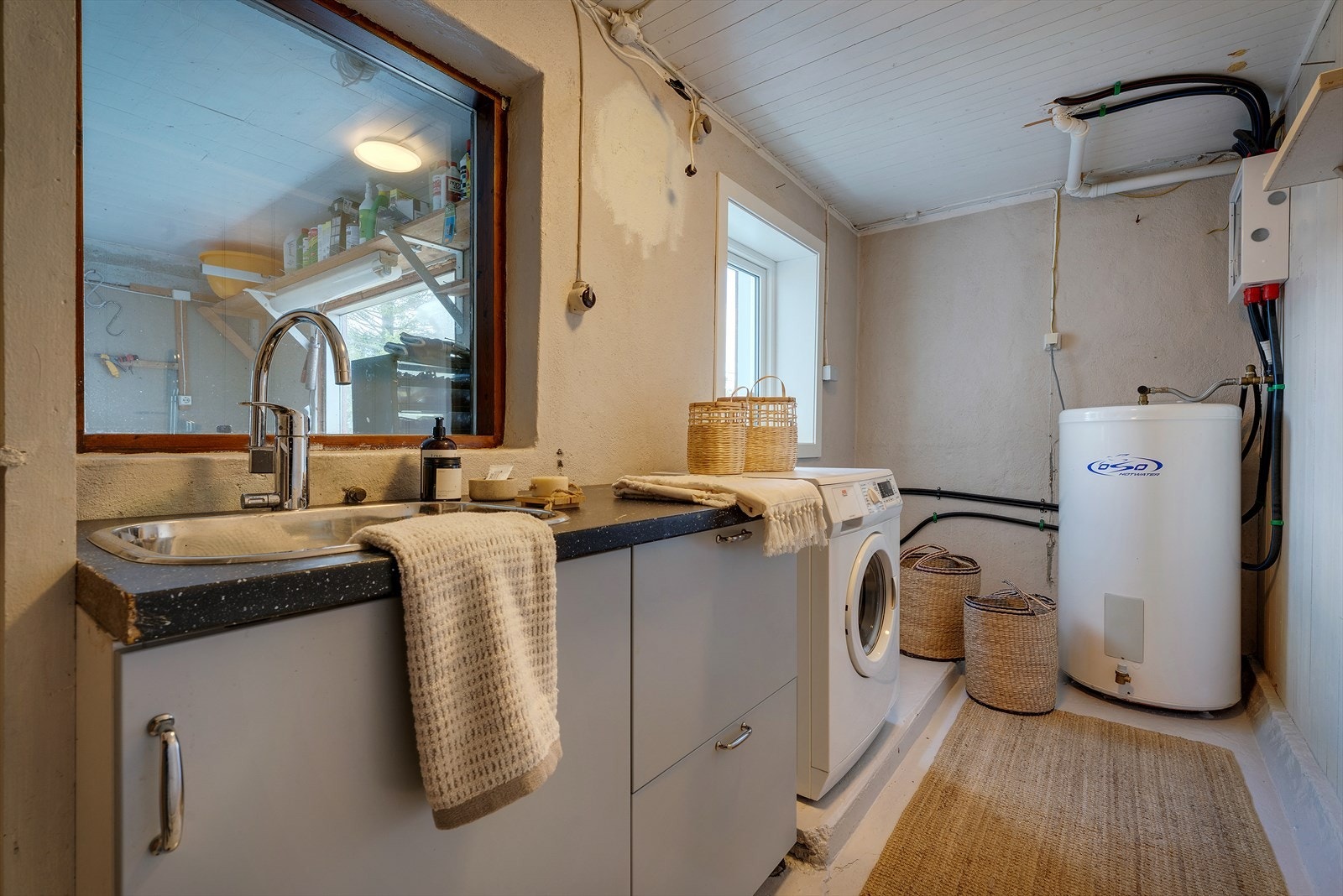 Praktisk vaskerom i underetasjen med utslagsvask, opplegg for vaskemaskin og en 200-liters varmtvannsbereder. Galleribilde
