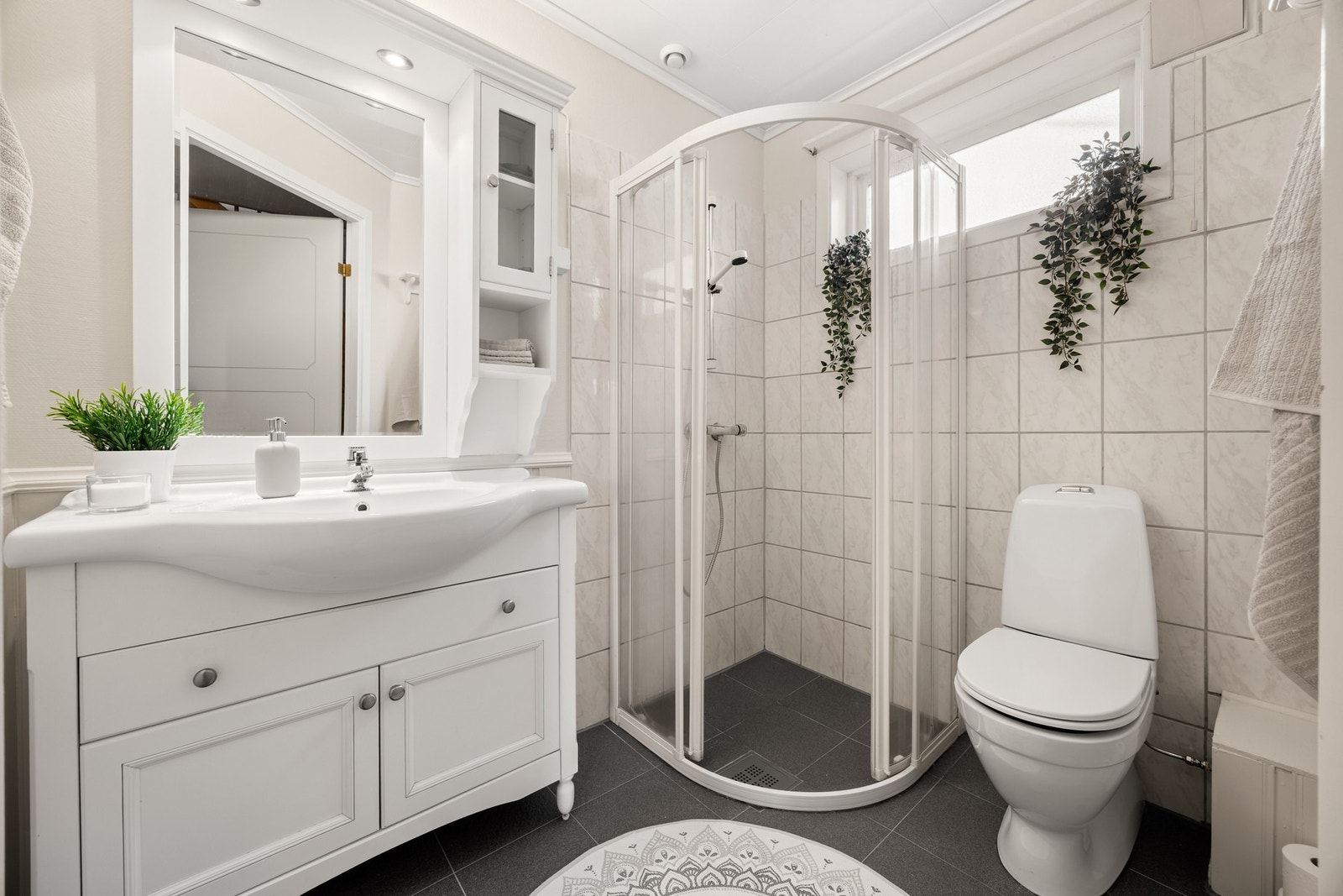 Badet har nedfelt servant i innredning, dusjhjørne og toalett. Galleribilde